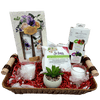 A gift basket containing decorative candles, hand cream collection, wipes, mini cologne spray, lip therapy kit, and an artificial flower pot, all arranged in a basket with a cellophane wrap.